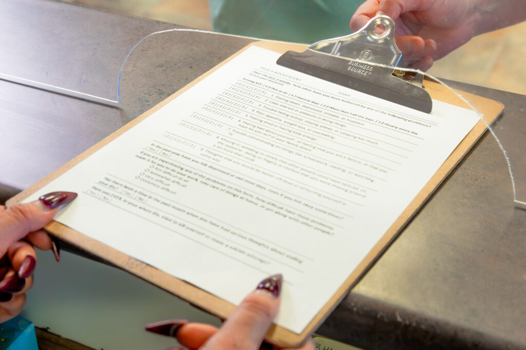 Man handing lady clipboard with paper on it to fill out prior to appointment.