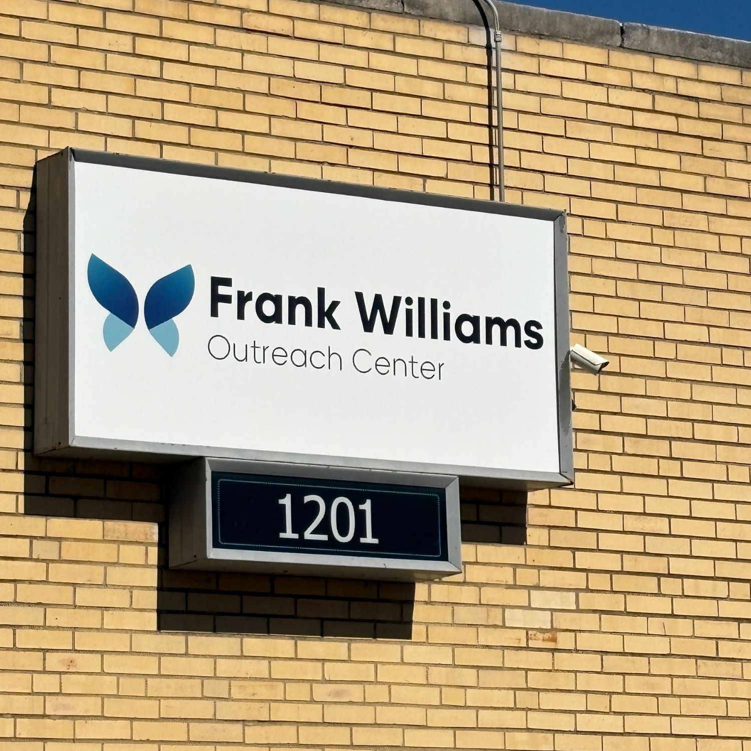 Outside of a brick building with a location sign of 1201 Frank Williams Outreach Center.