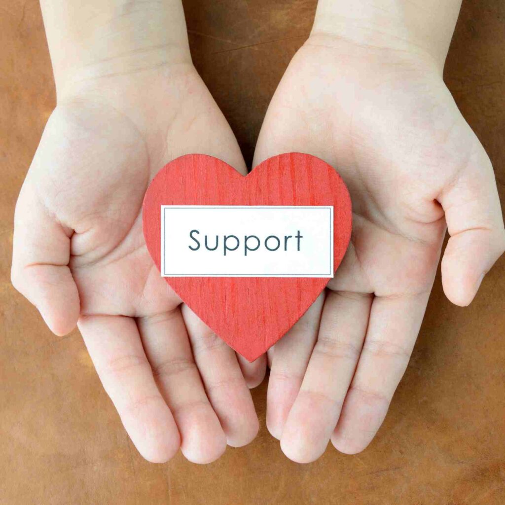Hand holding a heart that says support