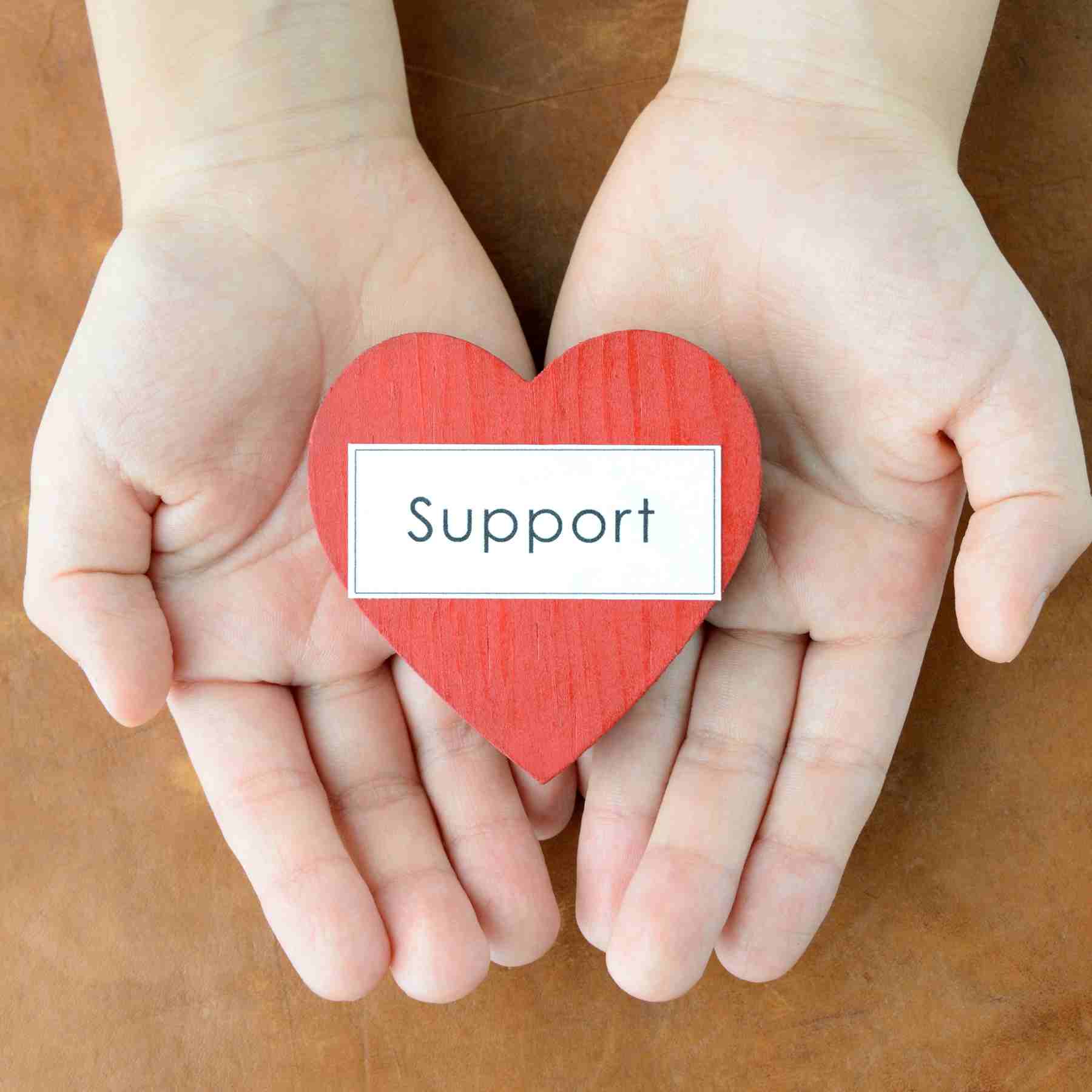 Hand holding a heart that says support